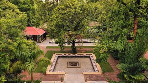 A courtyard with a central fire pit, surrounded by stone pathways and lush greenery. - Bandhav Vilas (Manpur)