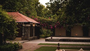 A courtyard with a stone building, a small pool, and lush greenery. - Bandhav Vilas (Manpur)