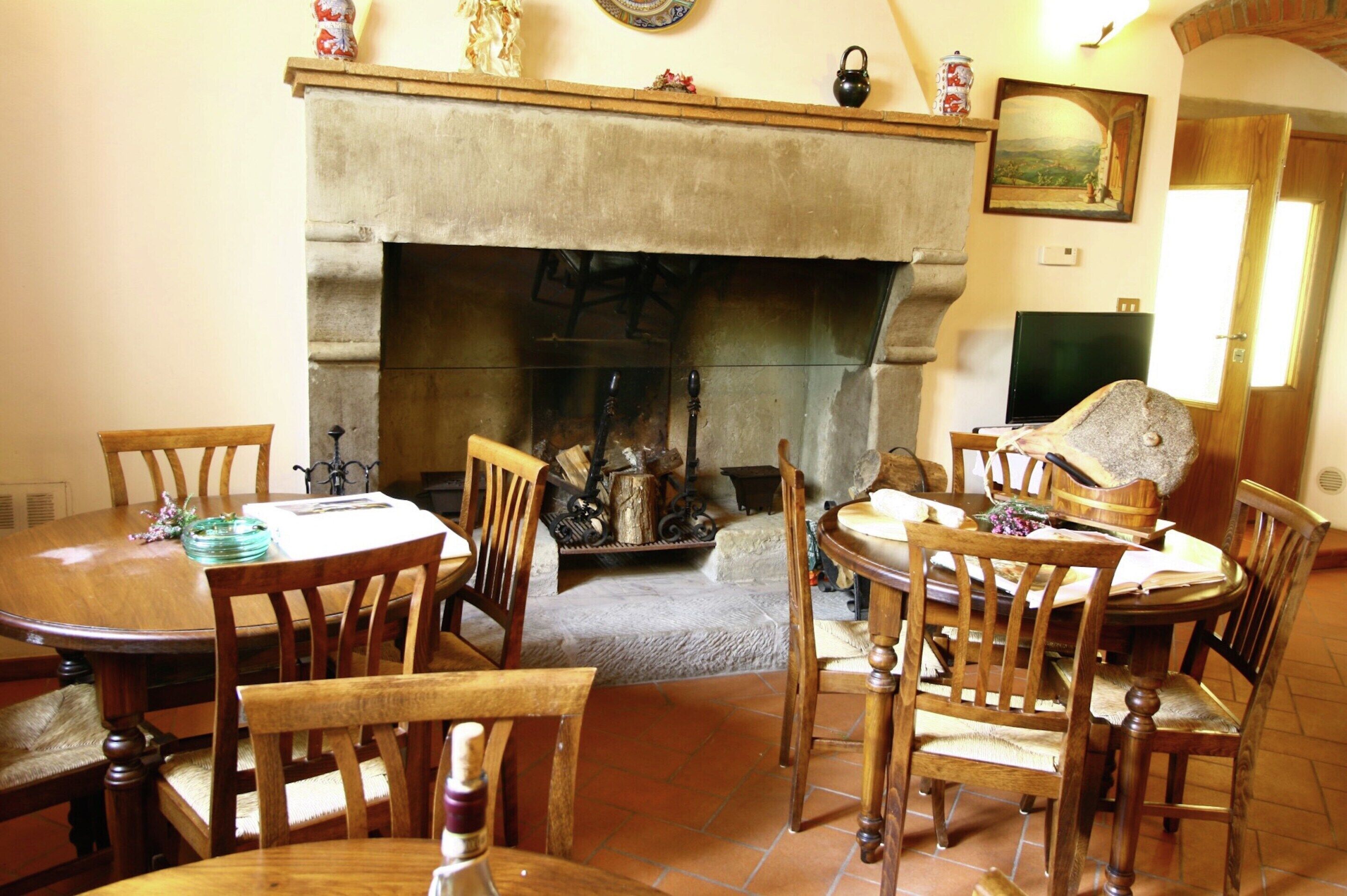 A dining area with a fireplace, wooden chairs, and a table set for four.