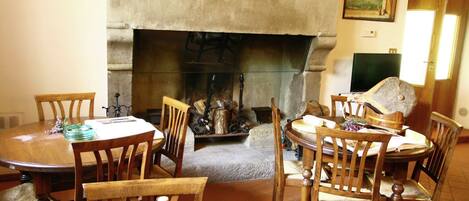 A dining area with a fireplace, wooden chairs, and a table set for four.