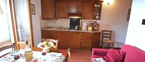 A cozy kitchen with wooden cabinets, a dining table set with plates, glasses, and a bottle.