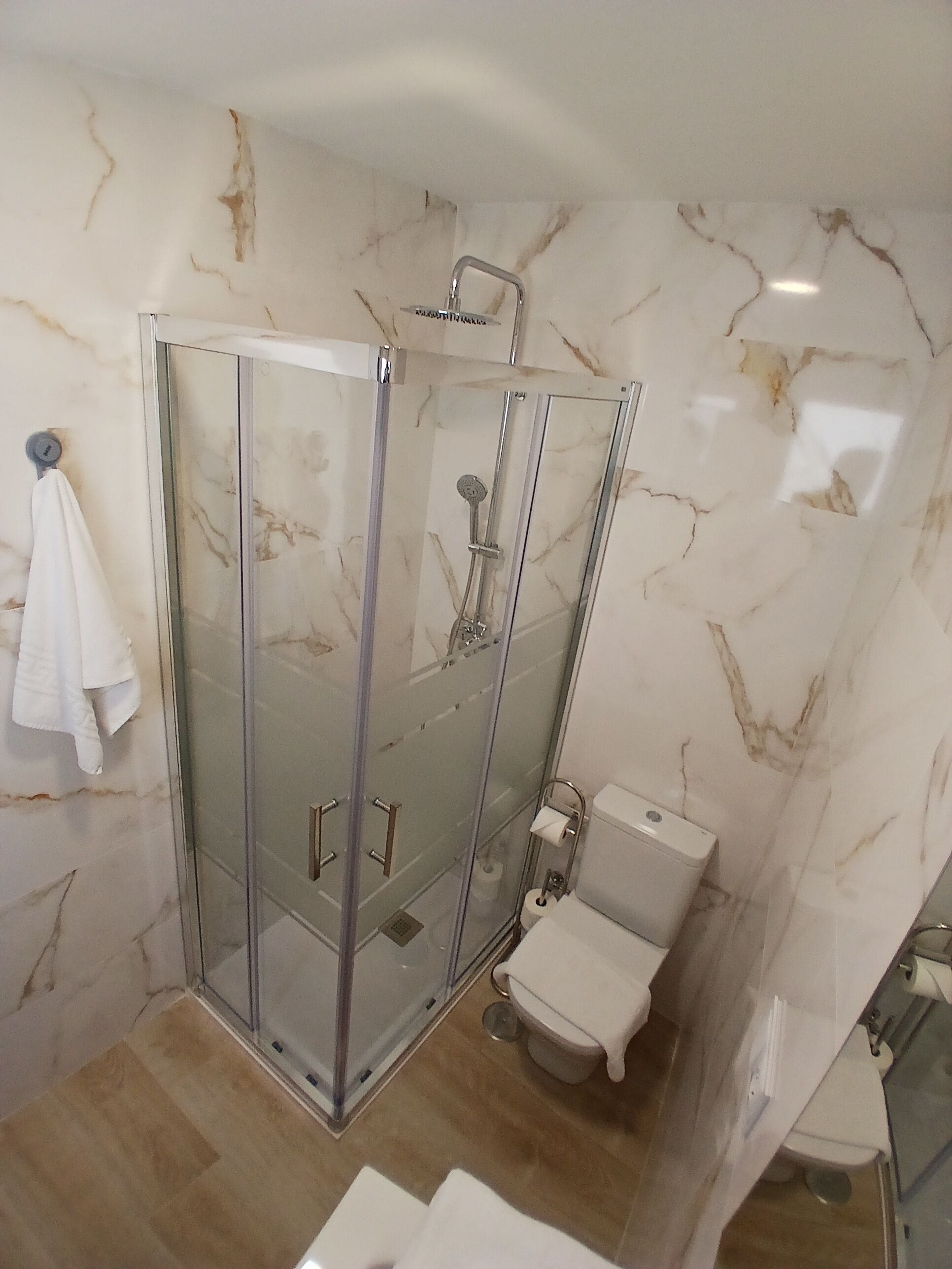 Un baño moderno con ducha envuelta en vidrio, inodoro y lavamanos.