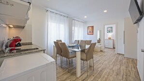 A modern kitchen with a built-in oven, a red kettle, and a granite countertop. - Apartamentos Chorrol (Benidorm)
