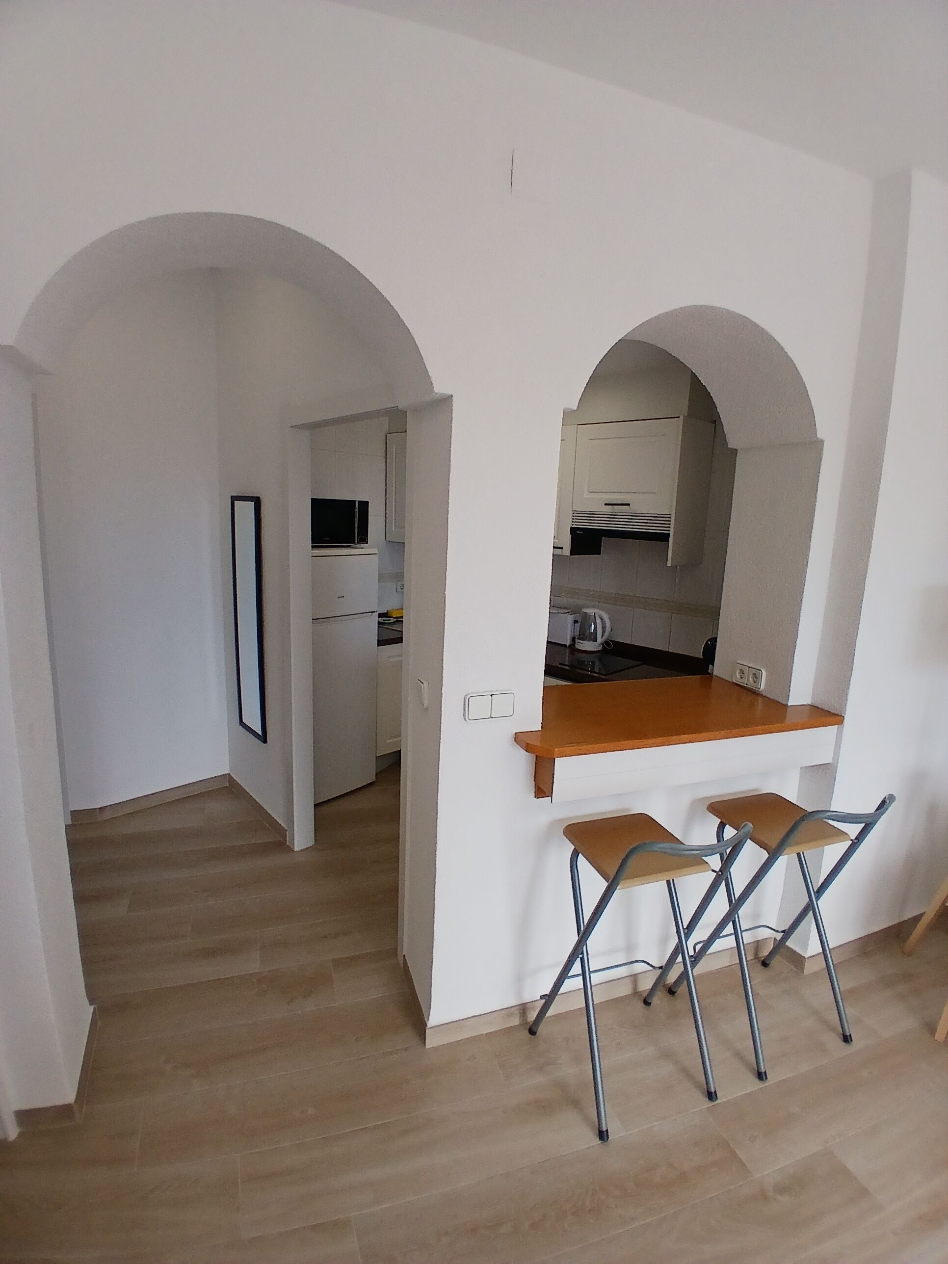 A kitchen with an open layout, a wooden countertop, and two foldable chairs.