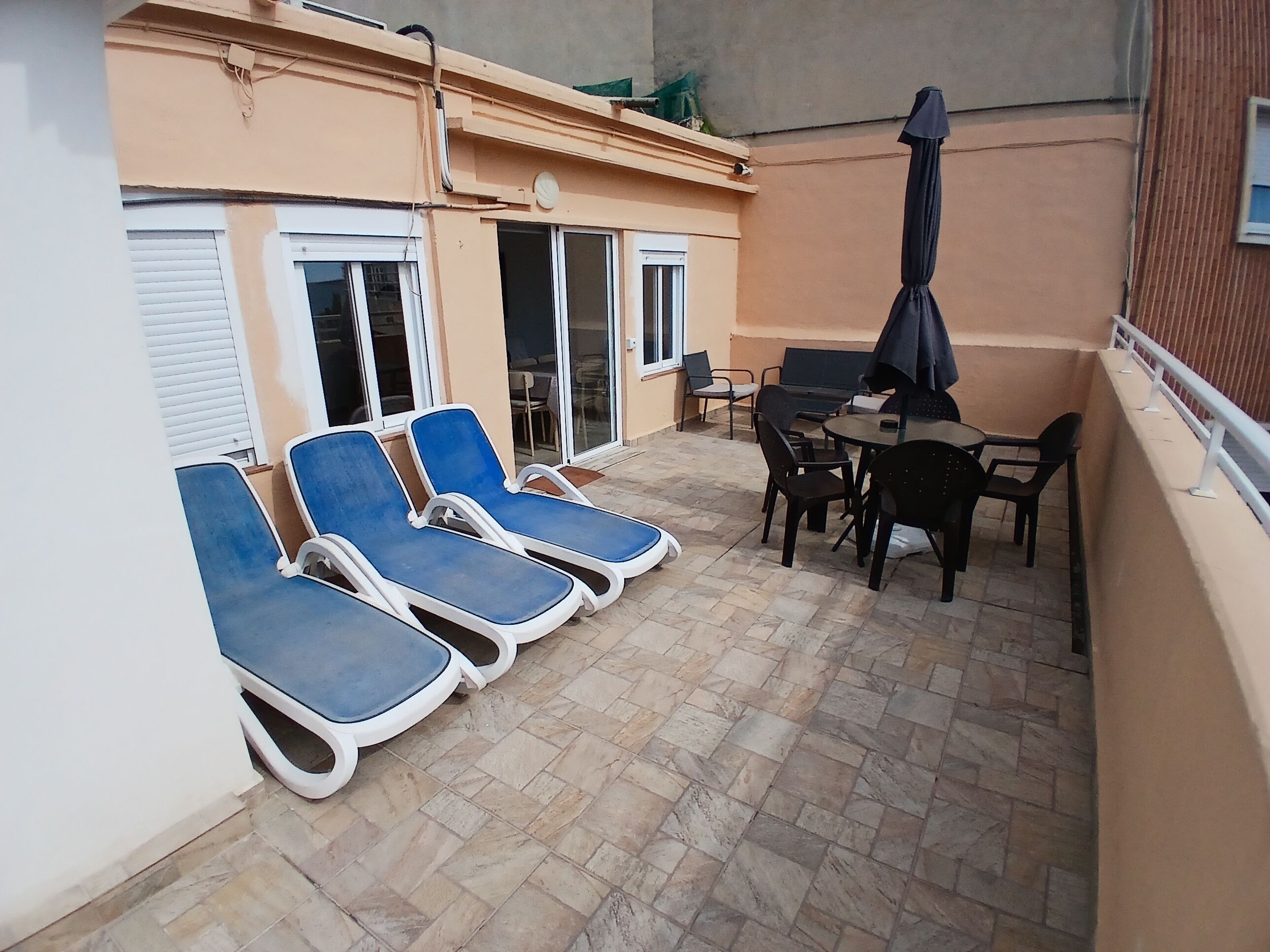 Een terras met lounge fauteuils, een tafel en stoelen.