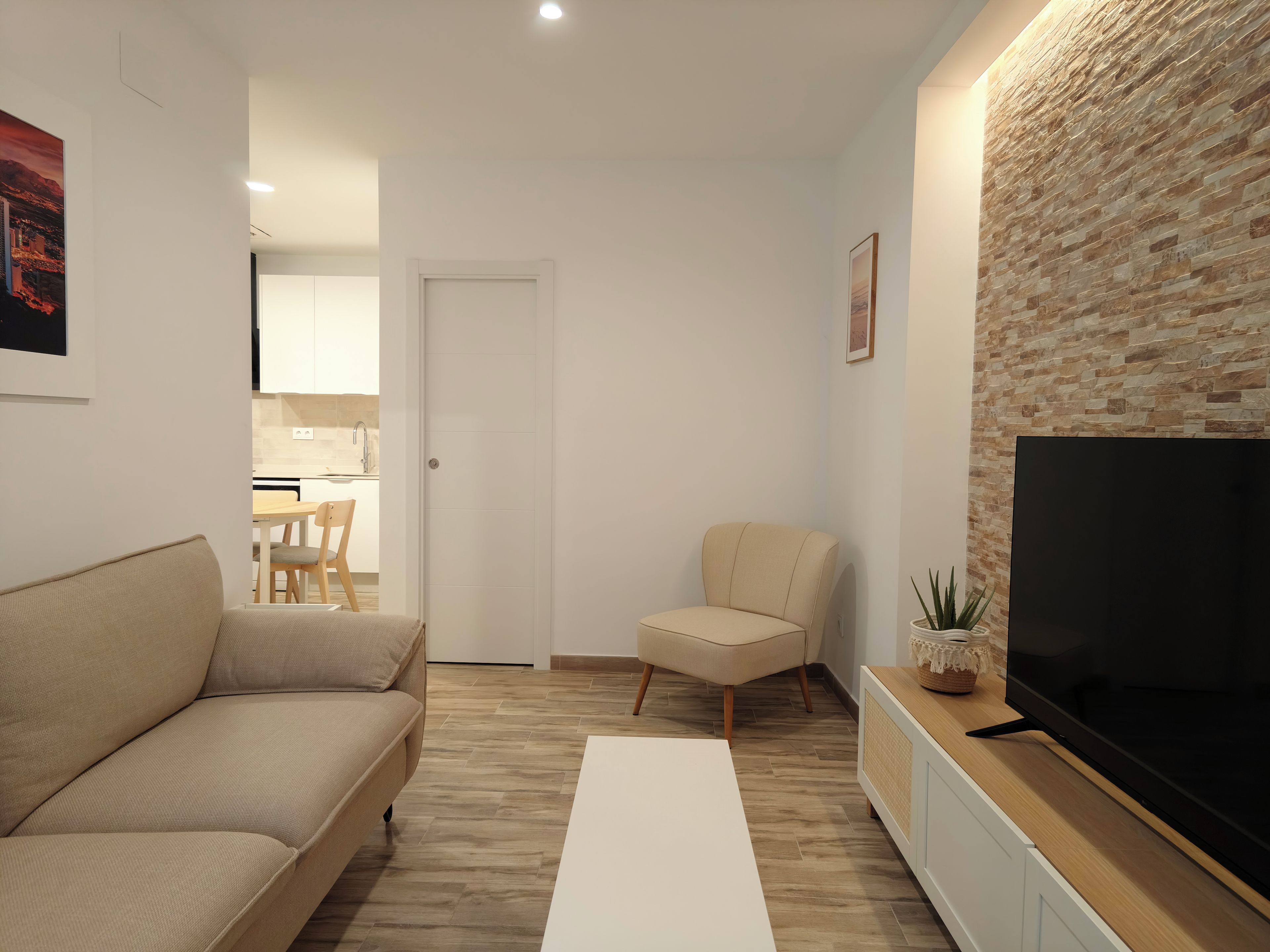 A modern living room with a sofa, a TV, a coffee table, and a stone wall.