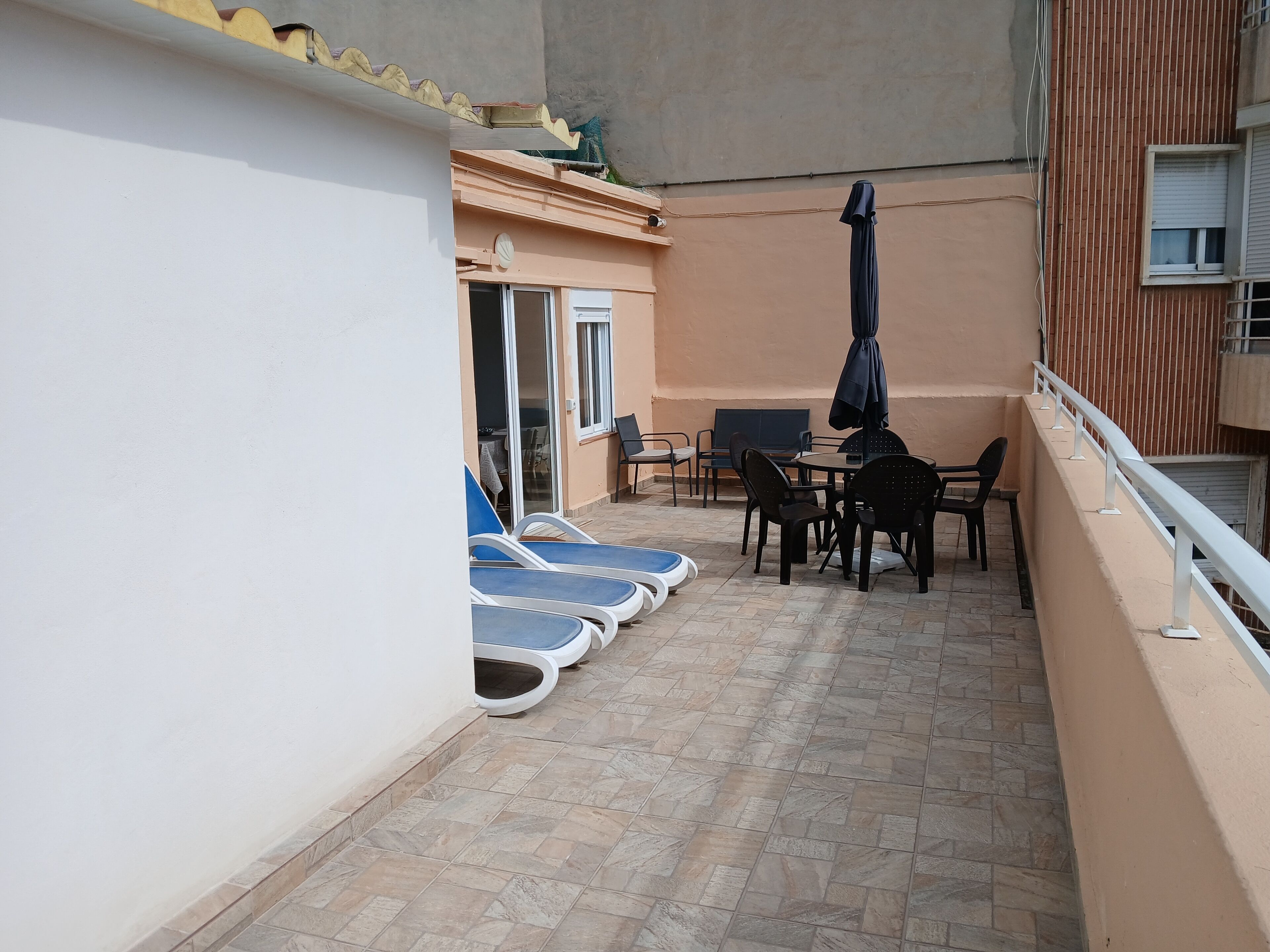Un balcone con tavolo e sedie, una piscina e un'area coperta.