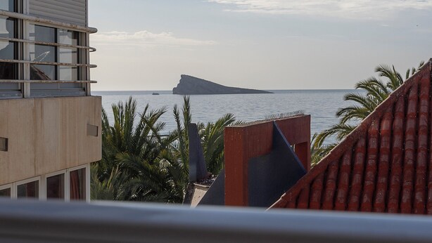 A coastal building with a view of the sea and a distant island. - Apartamentos Chorrol (Benidorm)