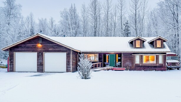 A wooden cabin with two garage doors, a covered porch, and a small front yard. - Home 20 Mi to Anchorage & Chugach State Park! (Chugiak)