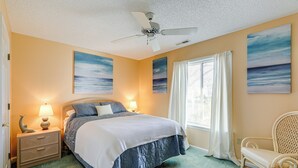 A bedroom with a bed, nightstand, lamp, chair, and artwork on the walls. - Half Mi to Beach: Bayfront Ocean City Condo, Deck (Ocean City)