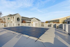 A rooftop with a large, flat, blue surface, possibly for solar panels, surrounded by buildings with balconies and a gated entrance.