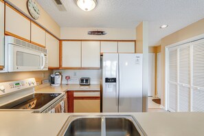A kitchen with a microwave, stove, sink, toaster, and refrigerator.