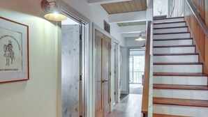 A hallway with wooden floors, a staircase, and a framed sign on the wall. - Kings Beach Retreat Near Lake Tahoe w/ Pool Access (Kings Beach)