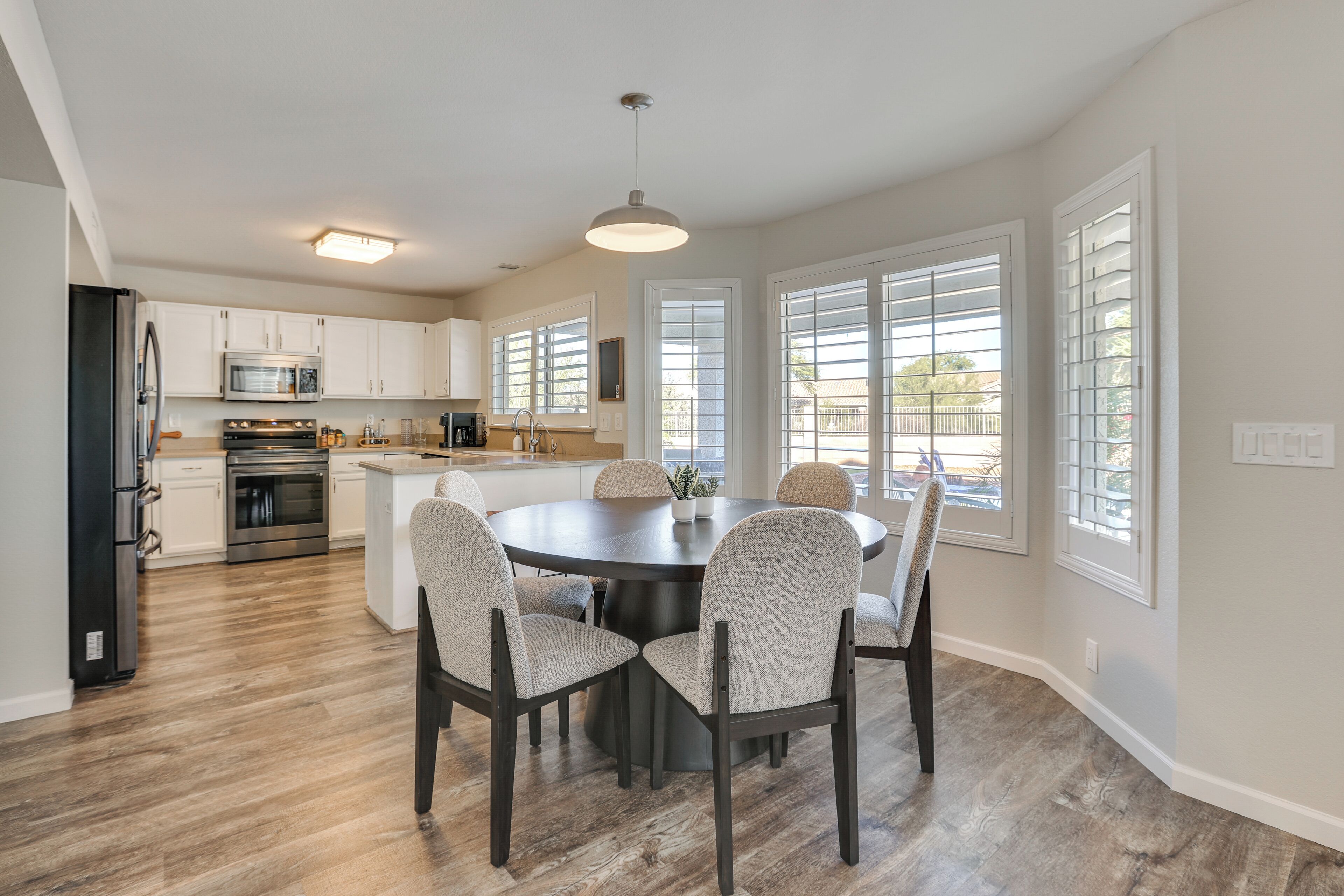 A modern kitchen with white cabinets, a central island, and a dining area with four chairs.