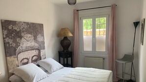 A bedroom with a bed, a Buddha painting, a lamp, a window with curtains, and a chair. - Peaceful accommodation 2 steps from amenities  (L'Isle-sur-la-Sorgue)