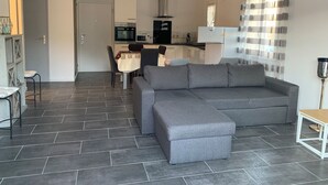 A modern living room with a grey sectional sofa, a dining area with a table and chairs, and a kitchen in the background. - Peaceful accommodation 2 steps from amenities  (L'Isle-sur-la-Sorgue)