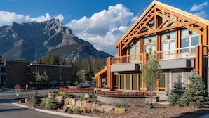 A modern building with large windows, a balcony, and a mountain backdrop.