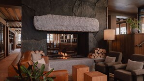 Ein gemütliches Wohnzimmer mit Kamin aus Stein, Ledersofas und Holztischen.