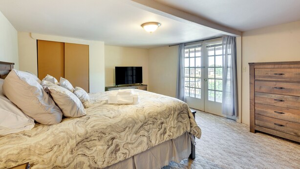 A bedroom with a large bed, a television, a dresser, and a window with curtains. - 11 Mi to Skiing: Valdez Home w/ Mtn Views! (Arroyo Seco)
