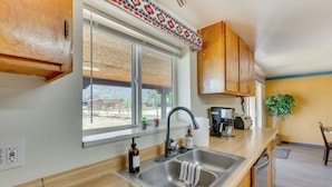 A kitchen with wooden cabinets, a stainless steel sink, a window with blinds, and a countertop with a coffee maker and a plant. - 11 Mi to Skiing: Valdez Home w/ Mtn Views! (Arroyo Seco)