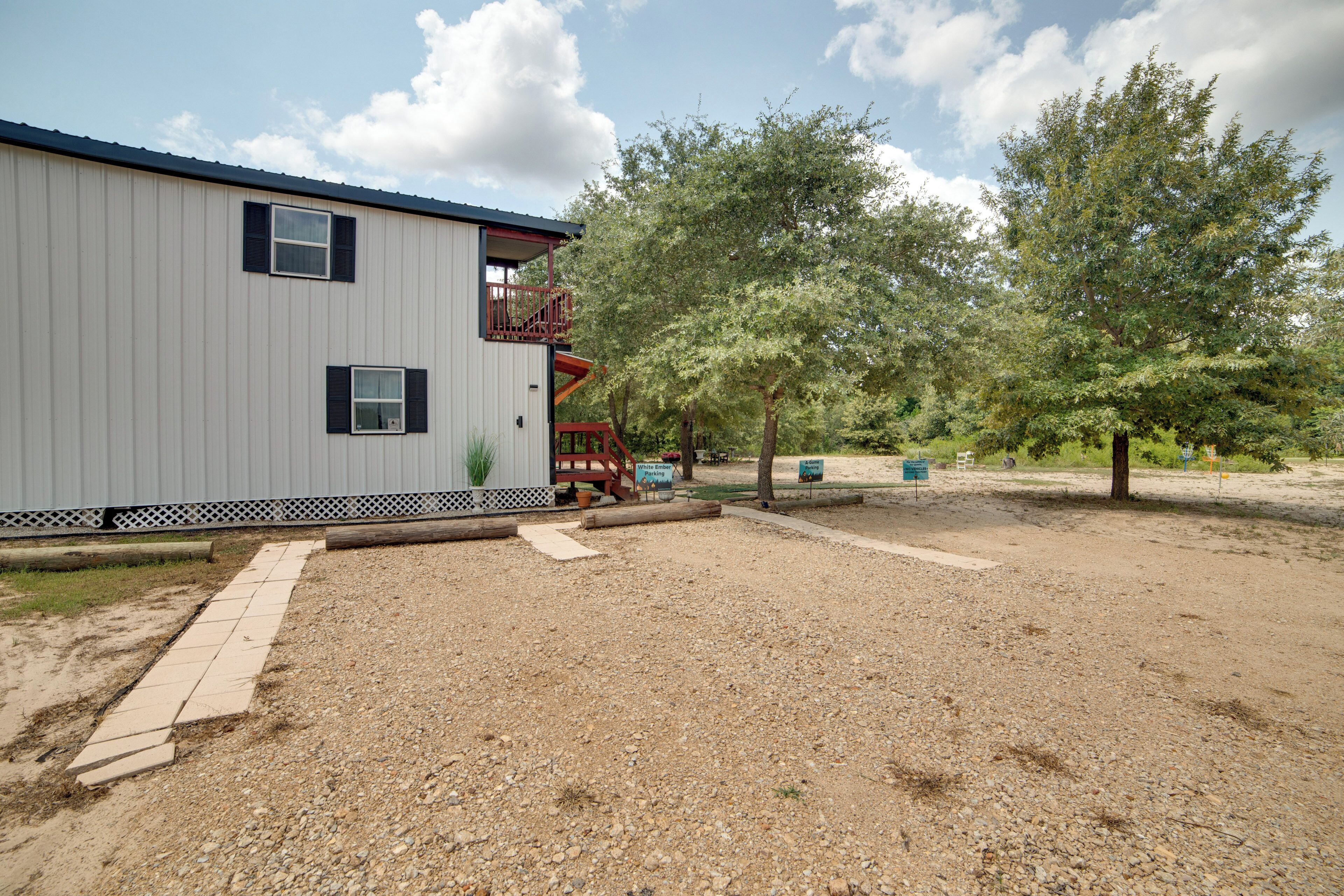 A building with a metal exterior, a wooden deck, and a gravel driveway.