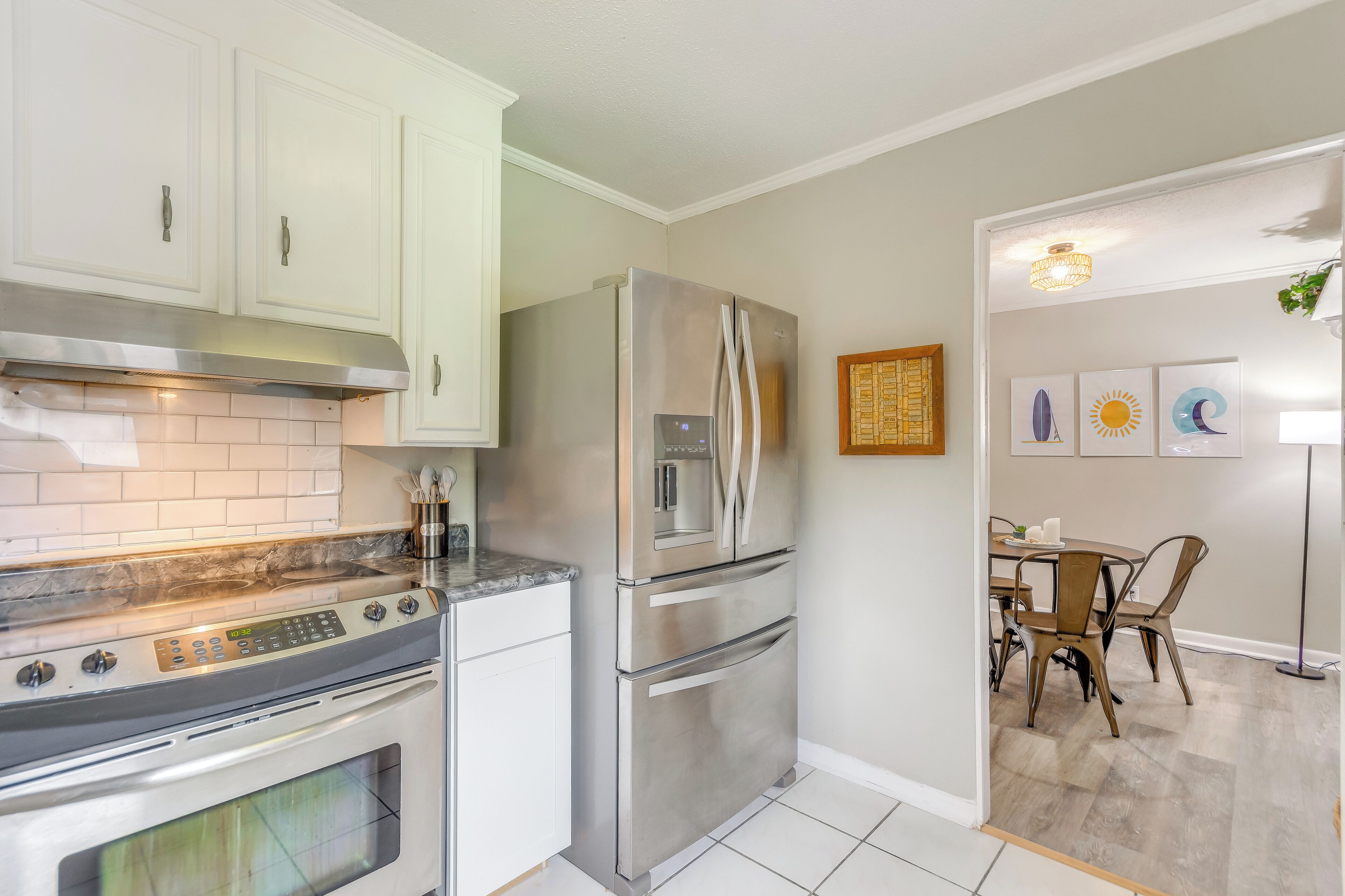 A modern kitchen with white cabinets, stainless steel appliances, and a tiled backsplash.