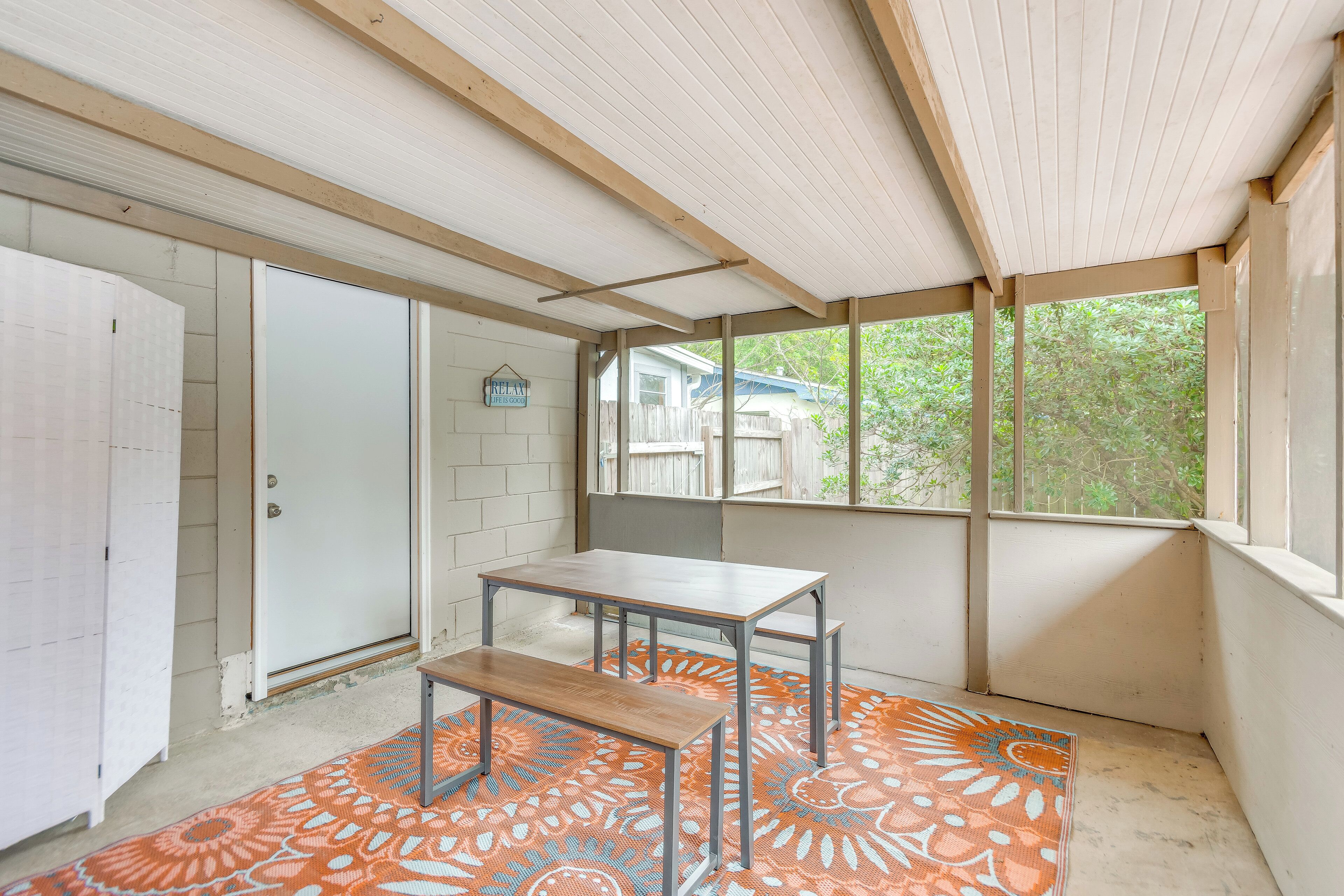 Une pièce avec un plafond en bois, une porte blanche, un banc et un tapis à motifs.