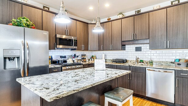 A modern kitchen with granite countertops, stainless steel appliances, and dark wood cabinets. - East End River Retreat: Dogs Welcome! (Madison)