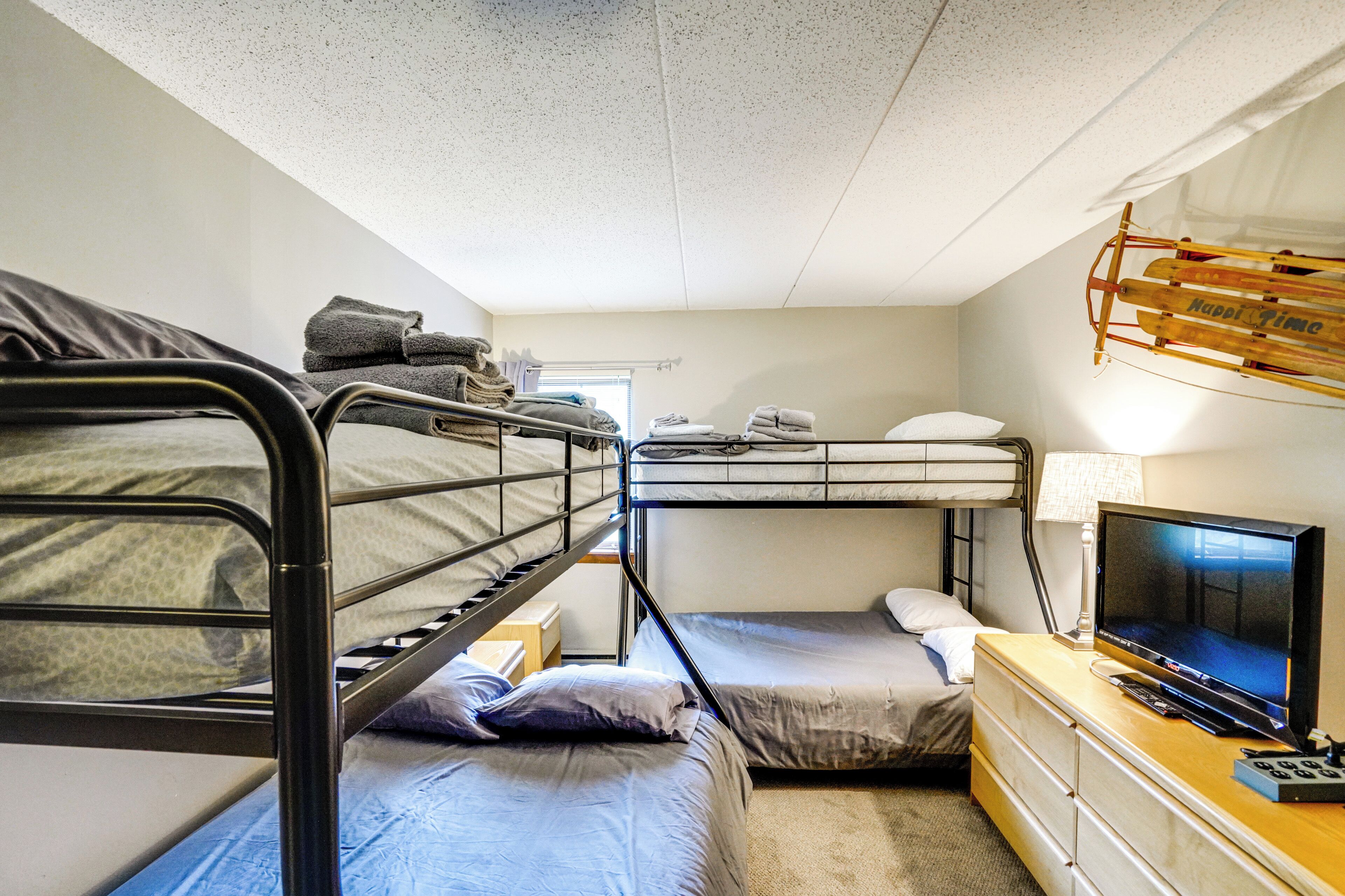 A bunk bed room with a television and a lamp on a dresser.