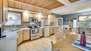 Una cocina con armarios de madera, electrodomésticos de acero inoxidable y una zona de comedor con mesa y sillas de madera.