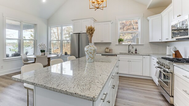 A spacious kitchen with white cabinetry, a granite countertop, and a large island.
