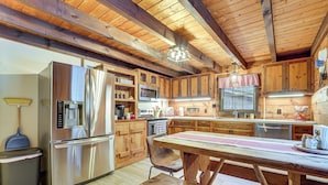 A modern kitchen with wooden cabinets, stainless steel appliances, and a wooden dining table.