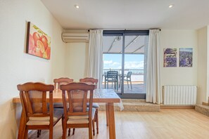 A dining area with a table and chairs, a view through a glass door, and artwork on the walls. - Apartment in Roses With Beachfront Access (Roses)