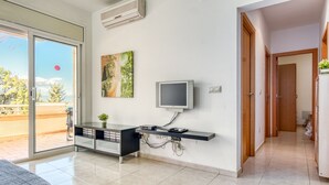 A modern living room with a sliding glass door to a balcony, a flat-screen TV mounted on a black console, and a painting on the wall. - Apartment in Roses With Waterfront Views (Roses)