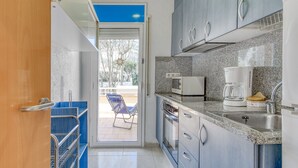 A compact kitchen with a built-in oven, a coffee maker, and a sink. There's a sliding glass door leading to an outdoor seating area. - Apartment in Roses With Waterfront Views (Roses)