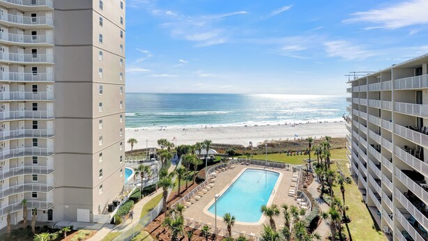 Hotel alto com piscina e vista para a praia.