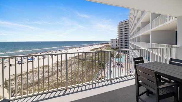 Un balcon avec vue sur la plage et l’océan, un espace piscine et une table à manger.