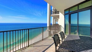 Un balcone con vista sull'oceano, un tavolo con sedie e una ringhiera.