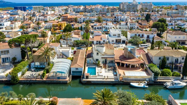 A coastal town with a marina, white buildings with red-tiled roofs, and a lighthouse in the distance. - Beachside Stay w/ Pools (Castello d'Empuries)