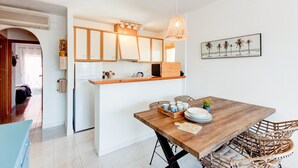 A modern kitchen with white cabinets, a wooden countertop, and a hanging light fixture. - Beachside Stay w/ Pools (Castello d'Empuries)