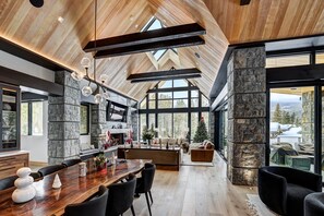 Living room featuring vaulted wood ceilings, a stone fireplace, and a live-edge wood table. - Snowy Owl Lux | Uniquely Modern in Shock Hill (Breckenridge)