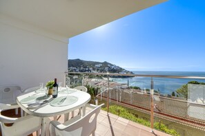 A balcony with a table set for two, overlooking a coastal town and the sea. - Apartment in Rosas Near Playa de Canyelles (Roses)