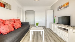 A modern living room with a sofa, a coffee table, a TV, and a cabinet. - Apartment in Rosas Near Playa de Canyelles (Roses)