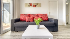 A modern living room with a grey sofa, red cushions, a white coffee table, and two abstract wall art pieces. - Apartment in Rosas Near Playa de Canyelles (Roses)