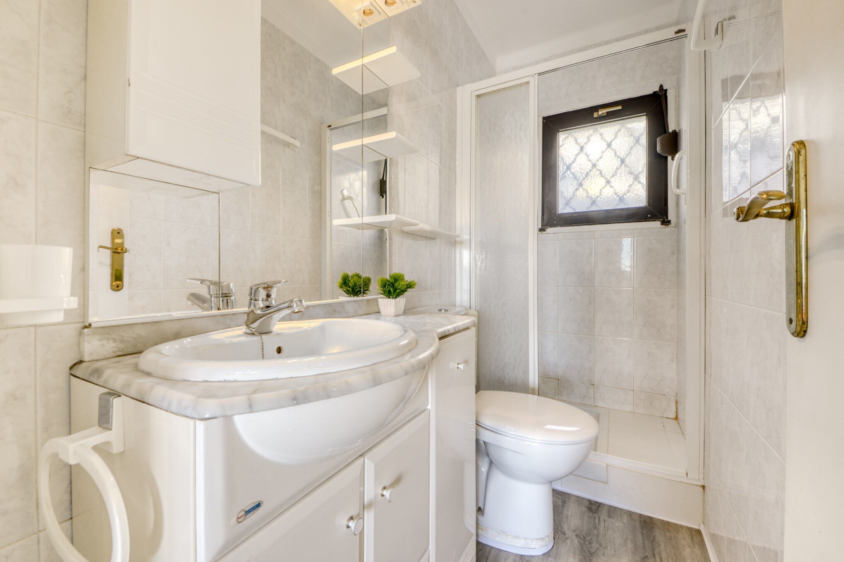 A modern bathroom with a marble sink, a toilet, and a glass-enclosed shower.
