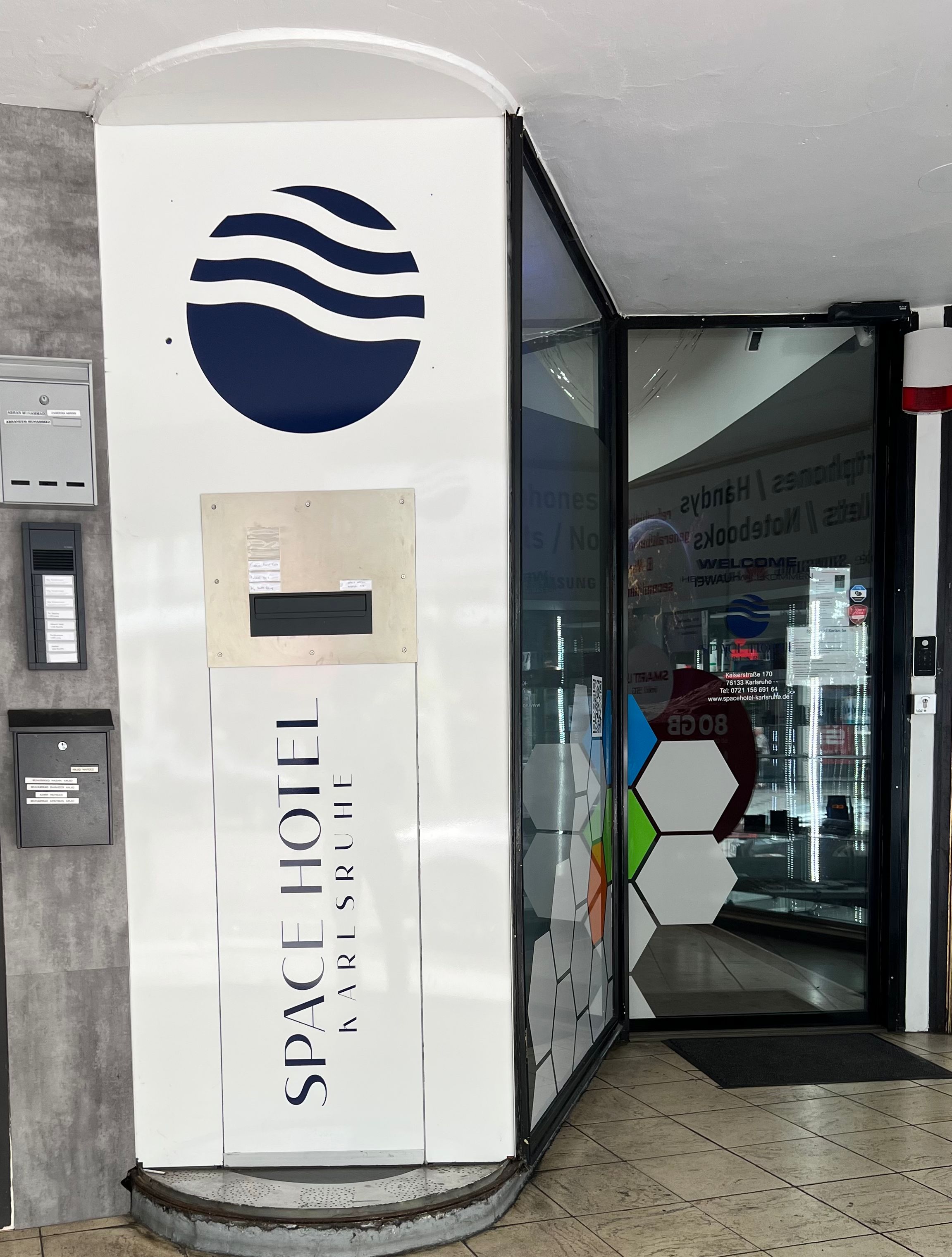 L’entrée d’un hôtel au design moderne, avec un logo, une enseigne d’accueil et une porte en verre.
