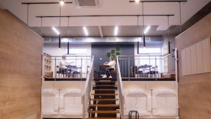 A modern interior with a central staircase, wooden panel walls, and a seating area with tables and chairs. - Spacehotel-Karlsruhe  (Karlsruhe)