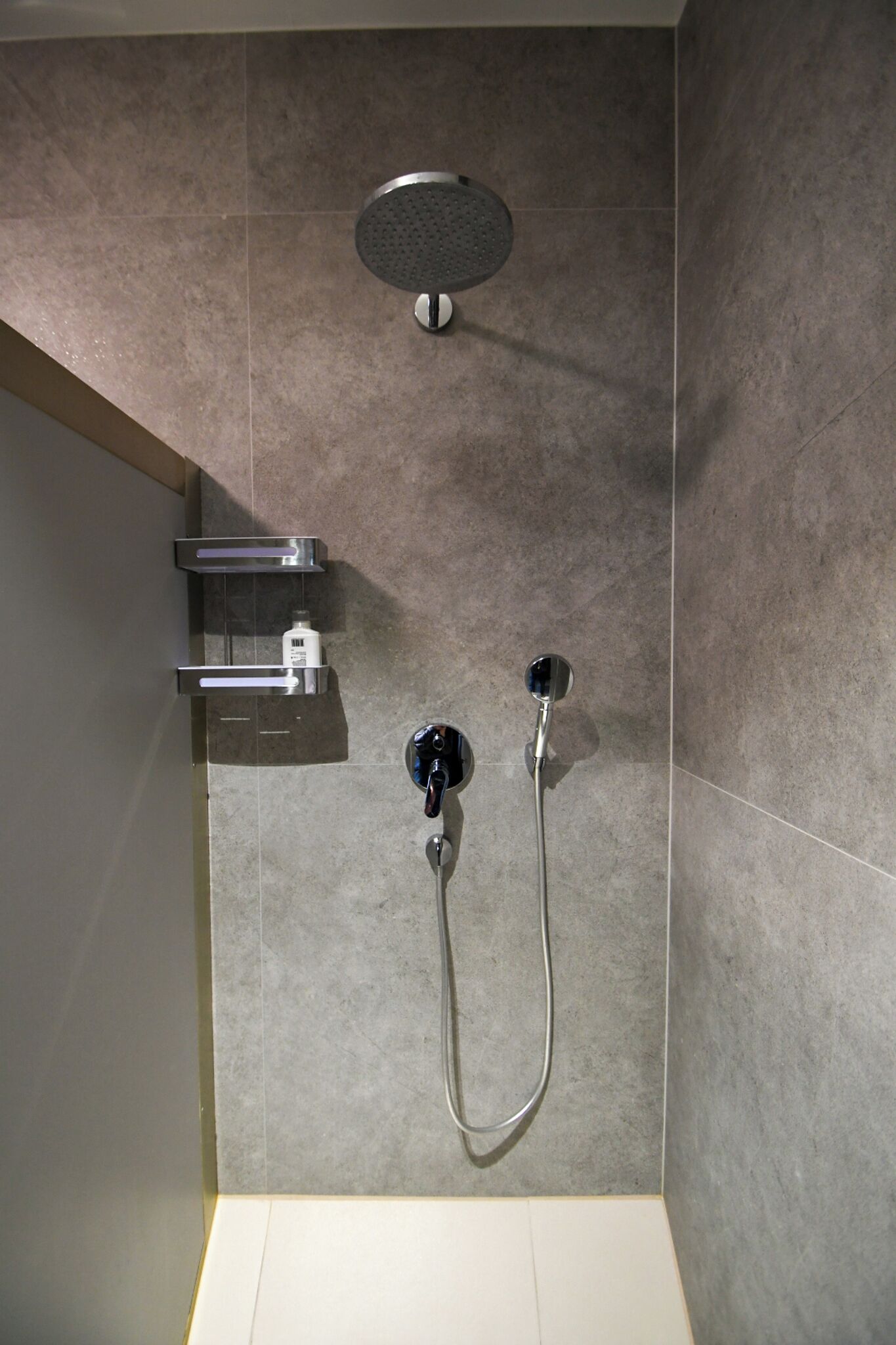 Eine moderne Dusche mit Handbrause und Armatur an der Wand.