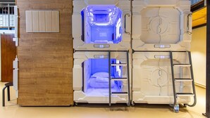 A modular room with a central bed and a ladder, surrounded by white panels with control panels. - Spacehotel-Karlsruhe  (Karlsruhe)