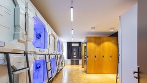 A hotel corridor with a row of spa tubs, wooden doors, and a tiled floor. - Spacehotel-Karlsruhe  (Karlsruhe)